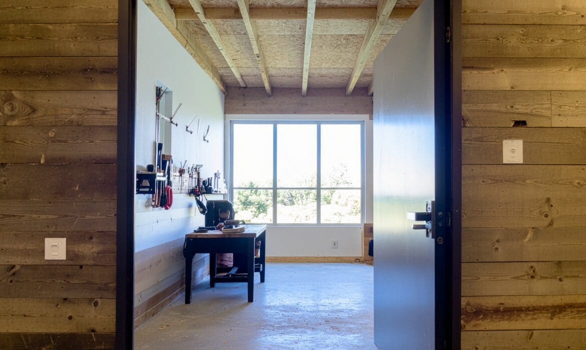 Post-frame workshop exterior with large overhead doors, designed for power, access, and durable finishes.